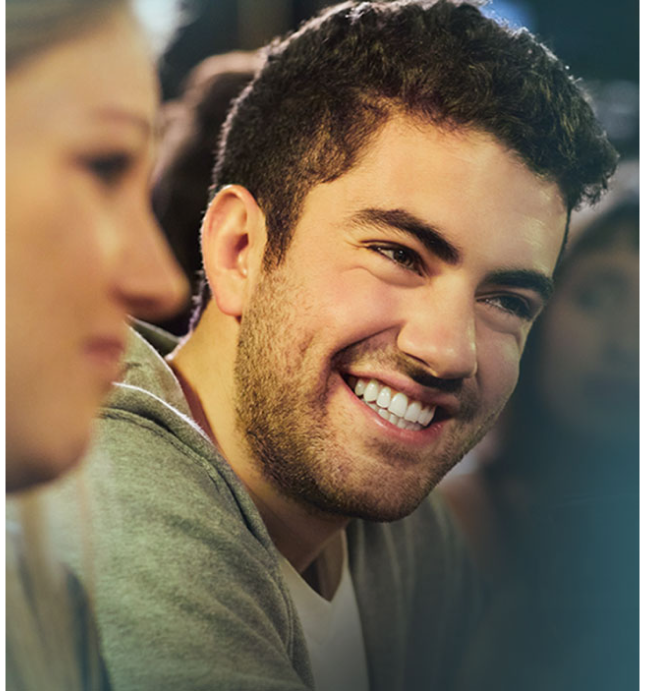 Man wearing green sweatshirt smiling in social setting