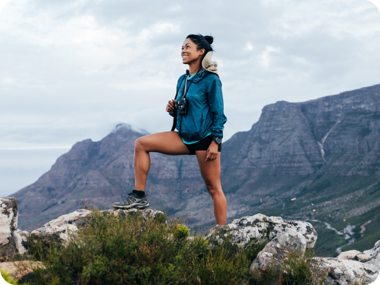 woman hiker standing on top of a mountain summit smiling looking up at the sky