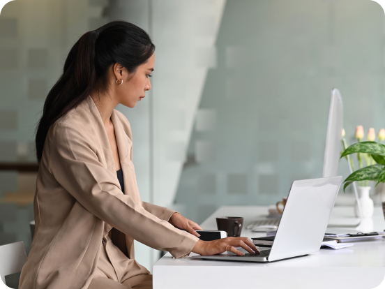 woman professional wearing a tan business suit working on a laptop while sitting at counter in office envirnonment