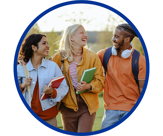 Three college-aged students walking outdoors, smiling and carrying books and backpacks, enjoying a conversation on a sunny day