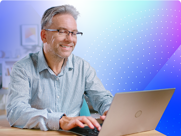 Smiling man wearing glasses working on a laptop in a brightly lit office or home workspace