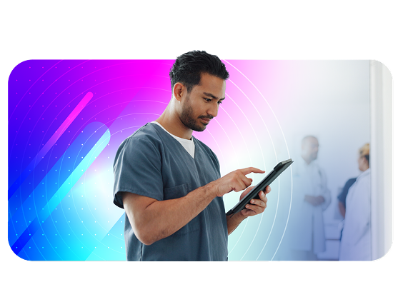 Male healthcare professional in scrubs using a tablet, with medical staff in the background