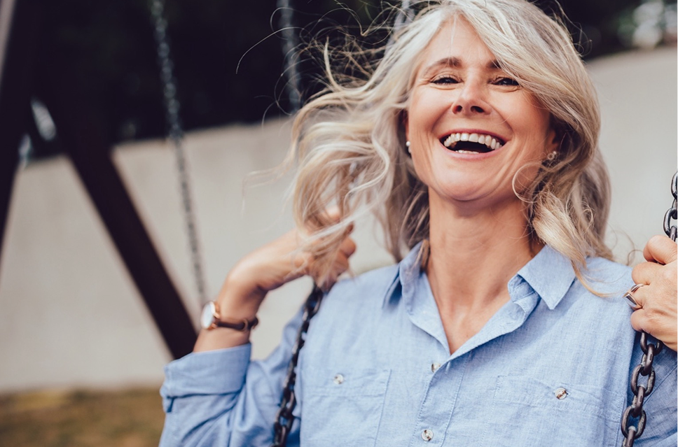 A smiling older woman sitting outdoors, symbolizing high patient satisfaction and freedom from glasses