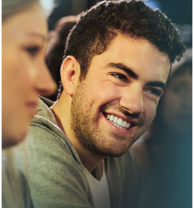 Man wearing green sweatshirt smiling in social setting