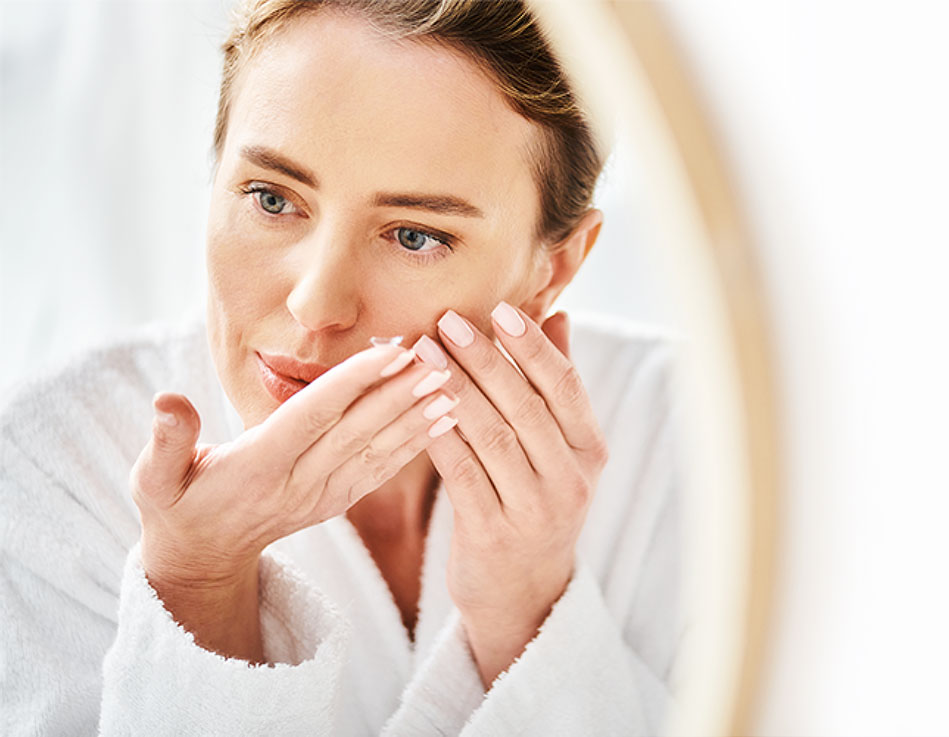 A woman in front of a mirror, carefully applying a contact lens to her eye